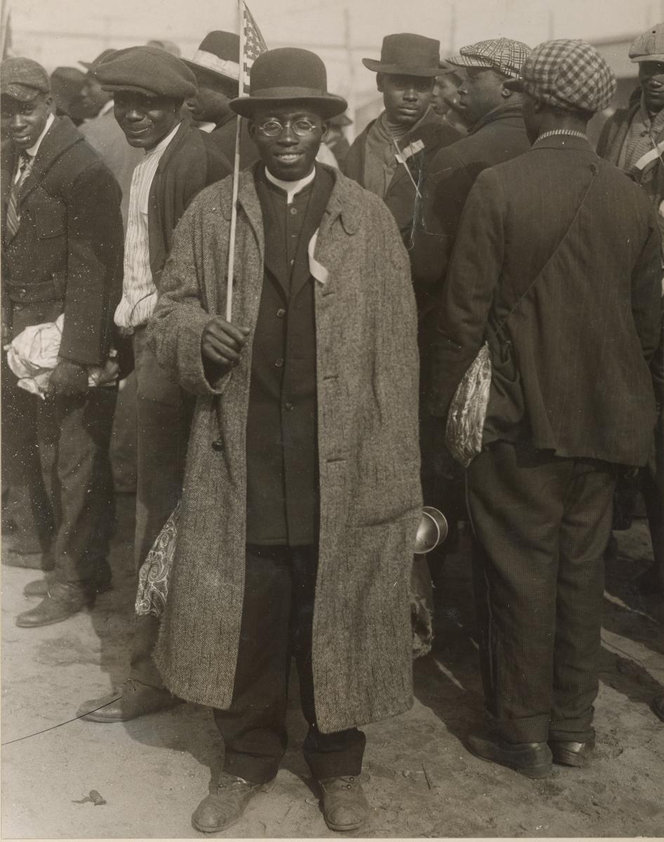 a man in long coat and top hat standing and smiling at the camera